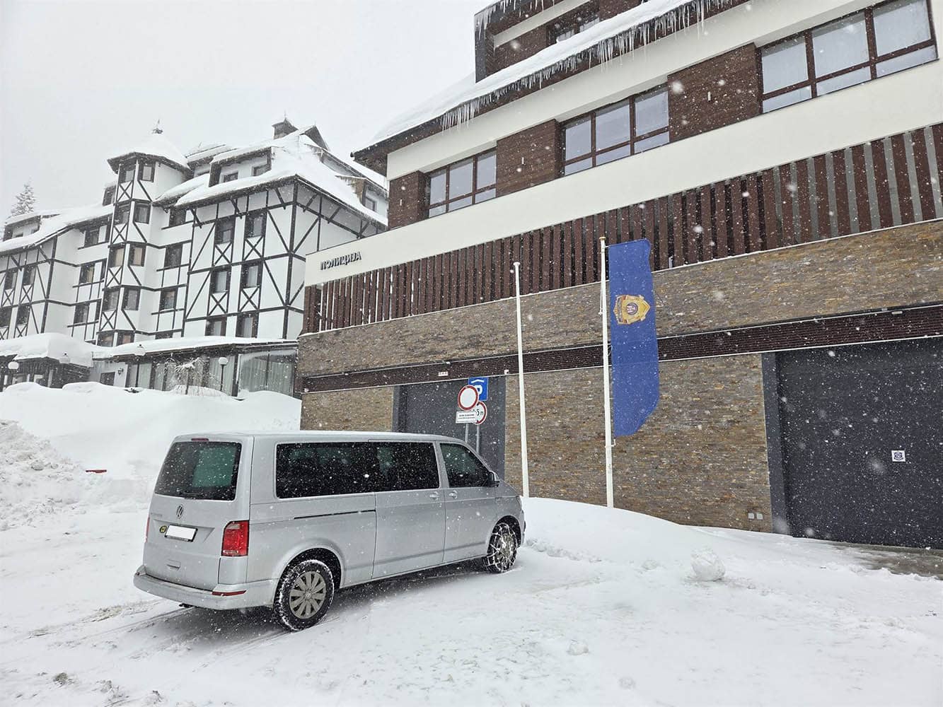 Beli Volkswagen kombi parkiran u snežnom planinskom naselju