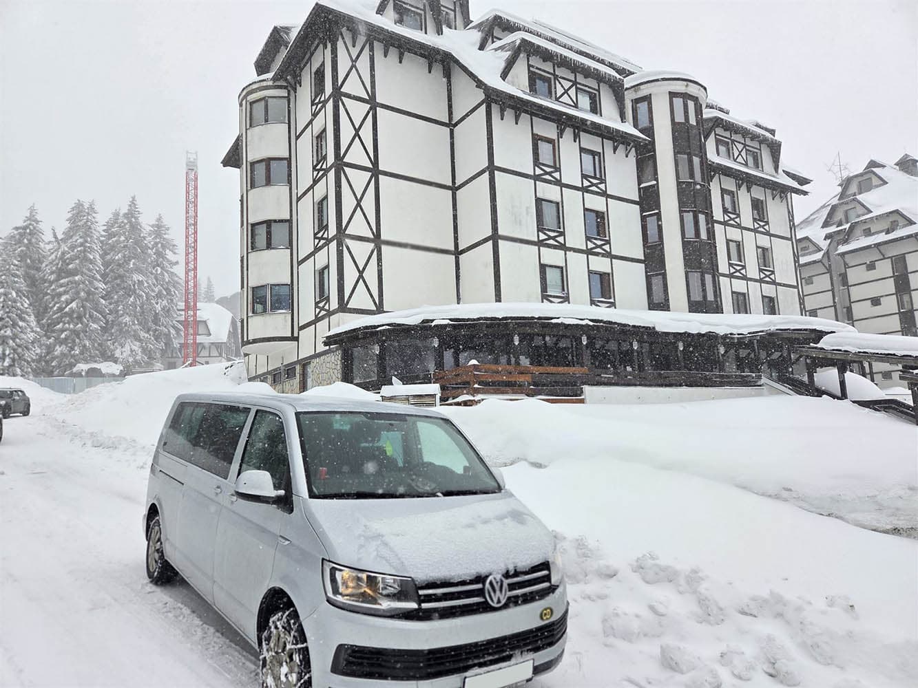 Beli Volkswagen kombi na snegu ispred hotelskog kompleksa