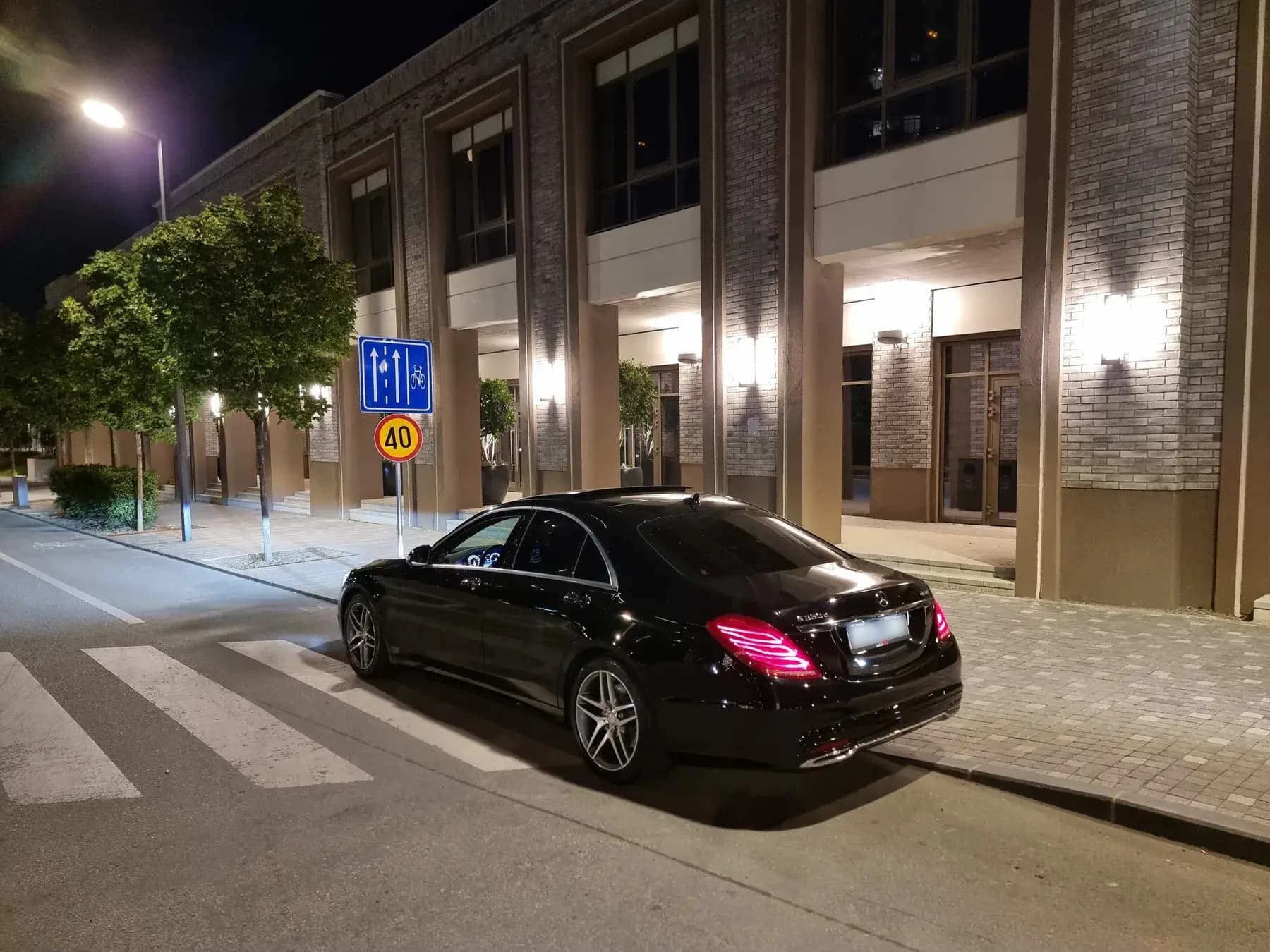 Tamna premium limuzina ispred aerodromskog terminala — VIP transfer